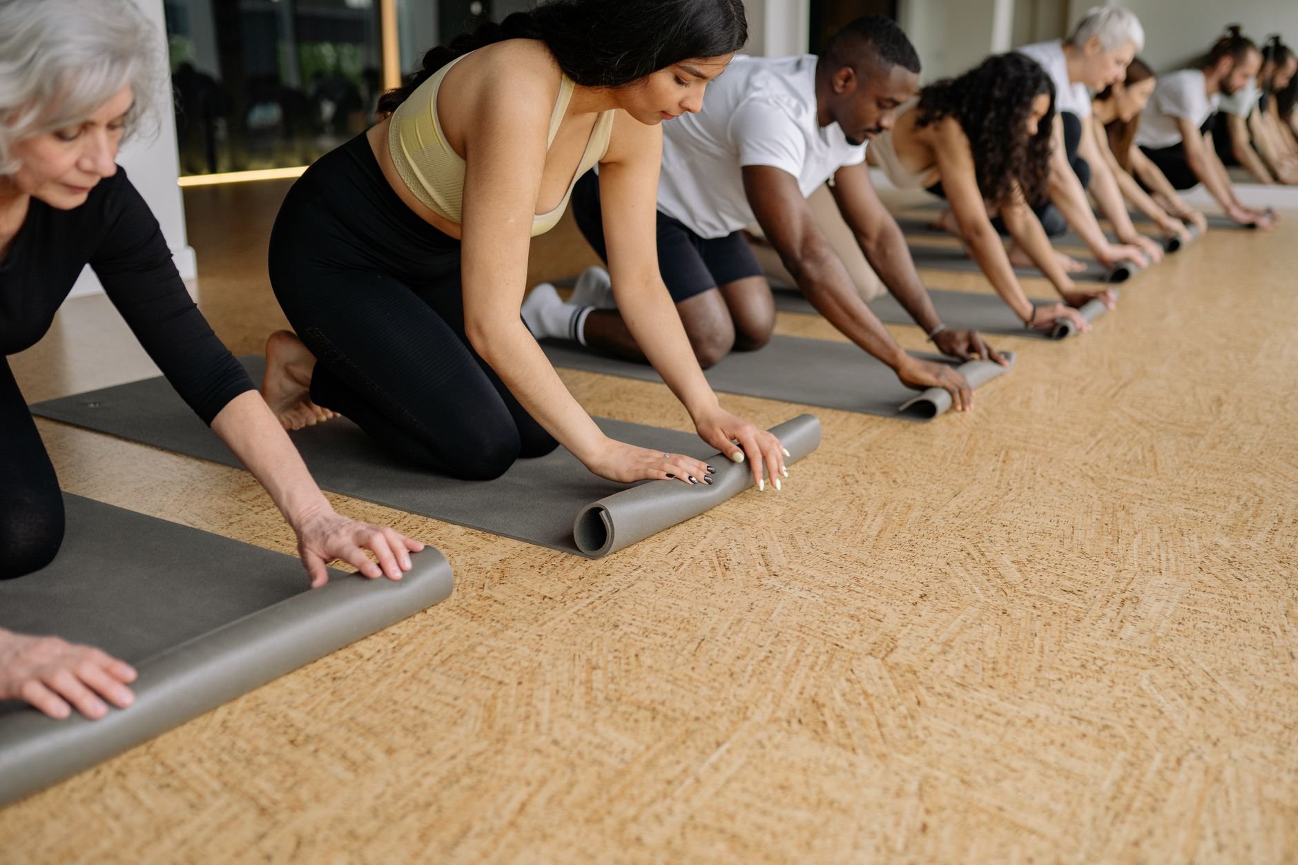 Group rolling yoga mats in a studio